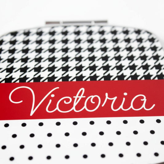 A close-up image of a mirror with a black and white houndstooth pattern and the name "Victoria" written in cursive on a red background.
