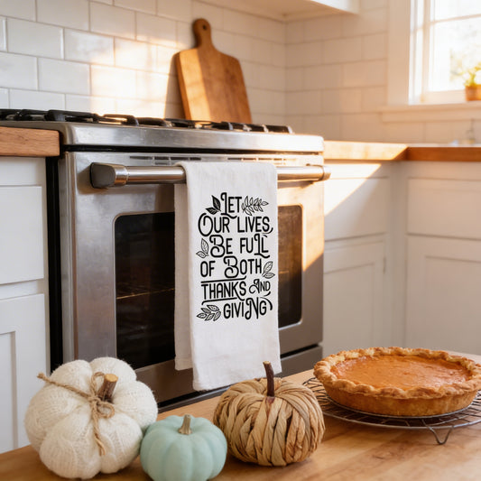 A kitchen counter with a pumpkin, a pie, and a towel with a message about Thanksgiving.