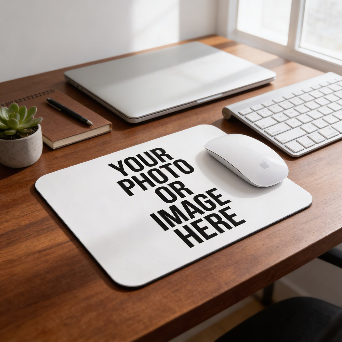 A wooden desk with a laptop, keyboard, mouse, and a plant. There is a mouse pad with the text "YOUR PHOTO OR IMAGE HERE" on it.