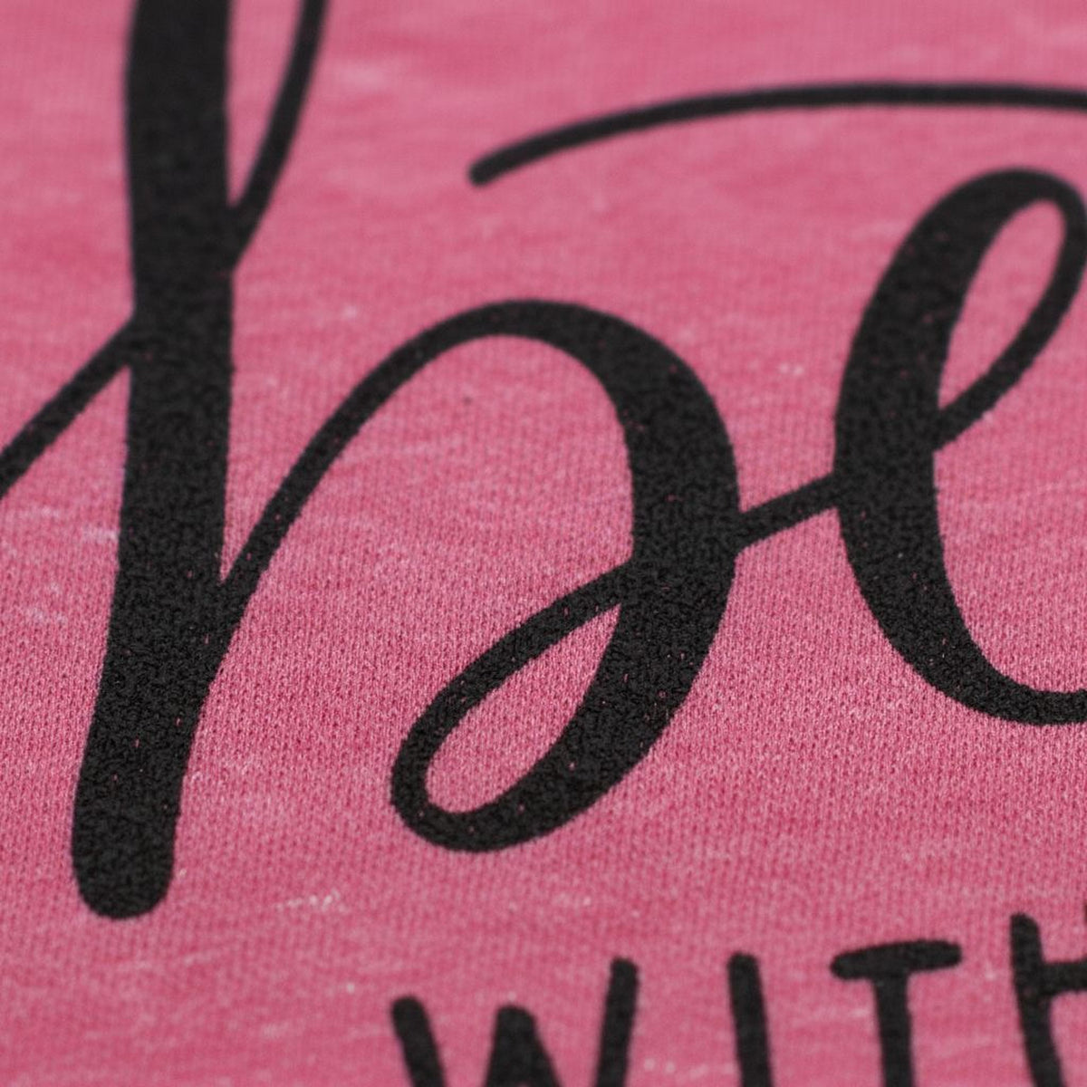 A close-up of a pink fabric with the word "be" printed in a cursive font.