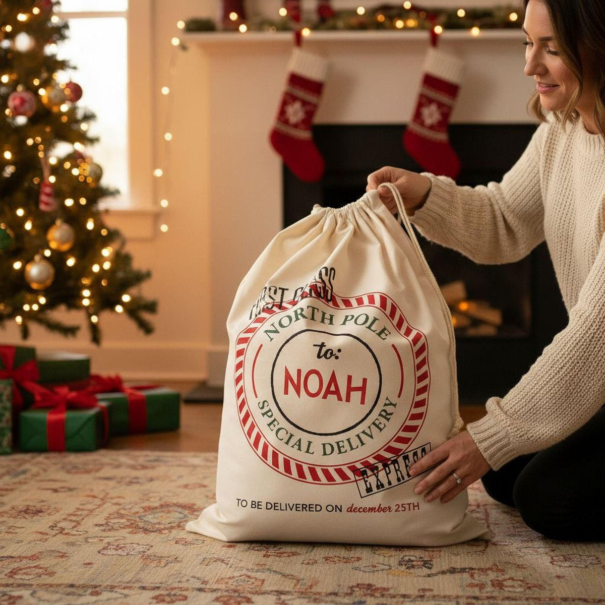 A woman is holding a large white bag with a red and white design, which appears to be a Christmas gift bag, in front of a decorated Christmas tree.