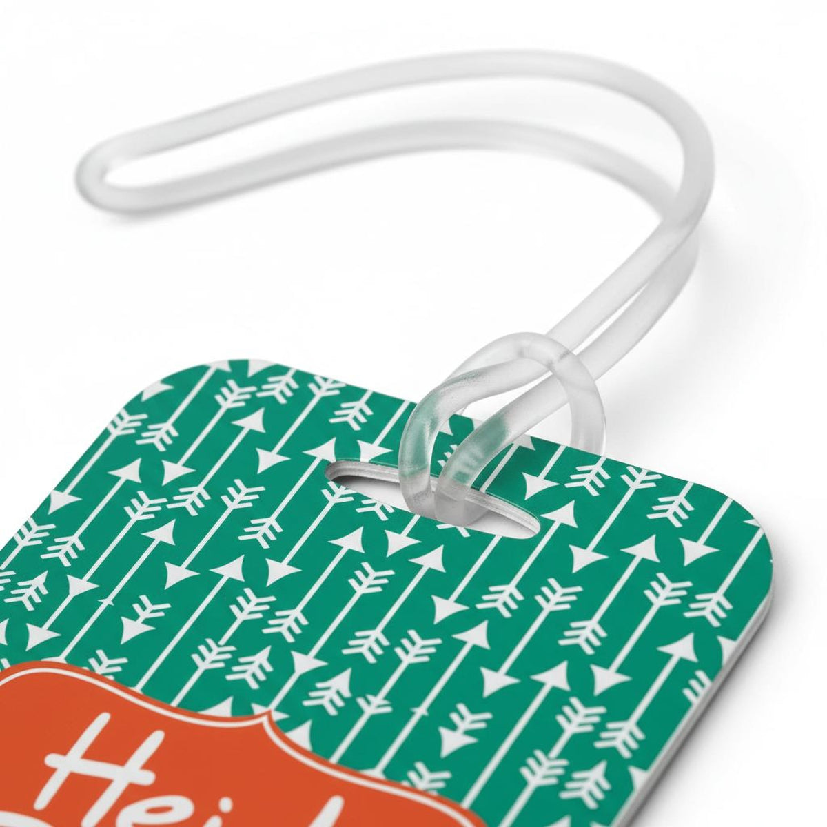 a green and white patterned luggage tag with a white handle and a clear plastic loop.