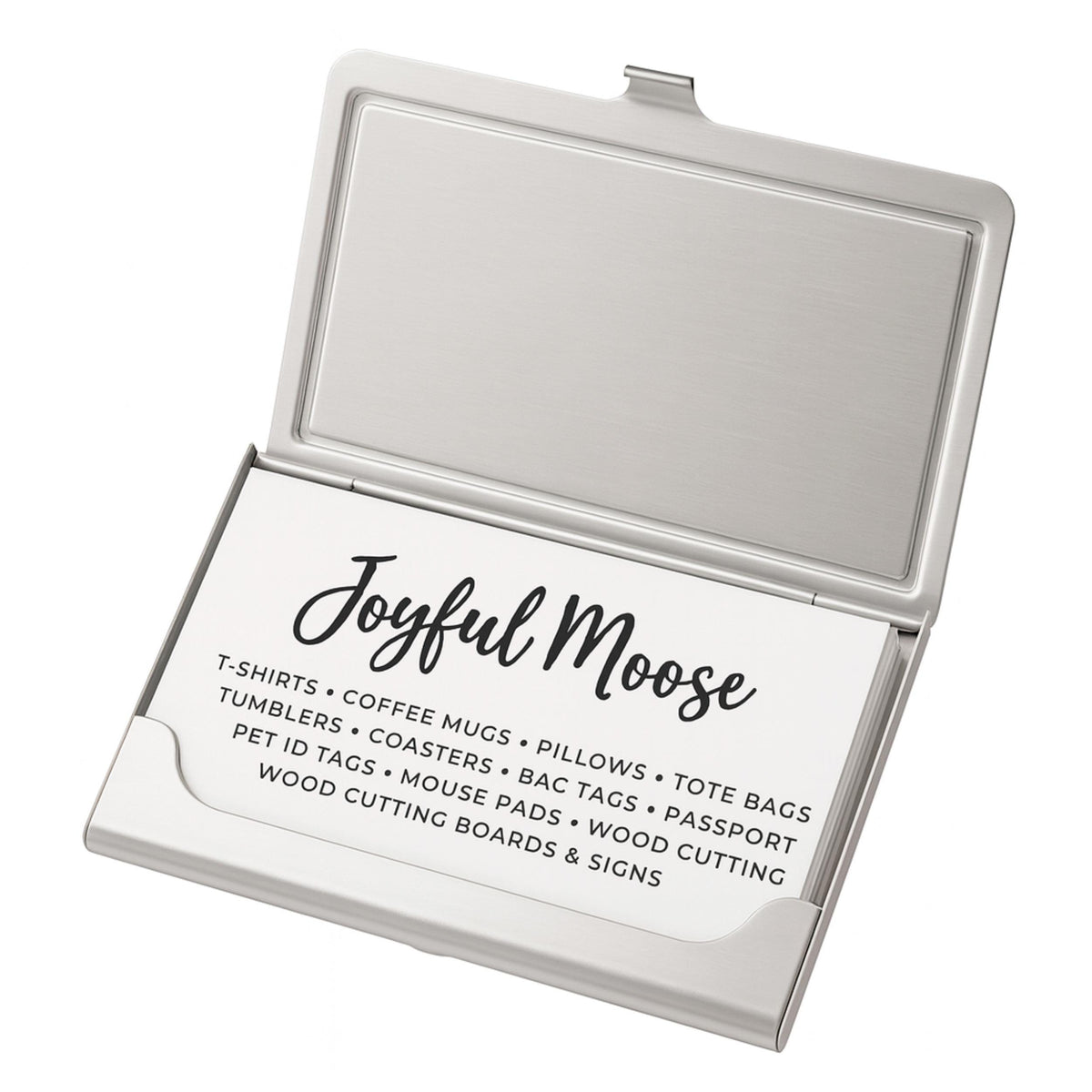 a business card holder with a business card inside. The card holder has a silver color and is open, revealing the card inside. The card contains text that provides information about the business, including the name 'Joyful Moose' and a list of items they offer, such as T-shirts, coffee mugs, pillows, tote bags, pet tags, coasters, and cutting boards.