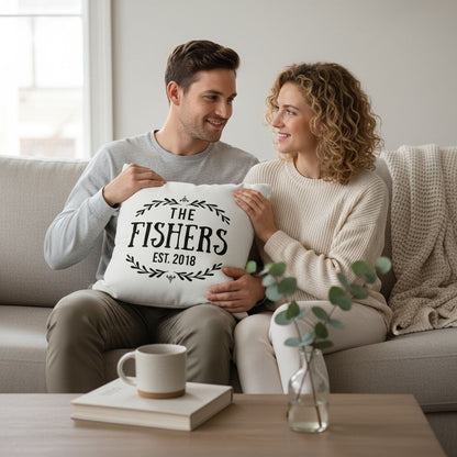 A man and a woman sitting on a couch, smiling and holding a pillow with the text "The Fishers EST 2018".