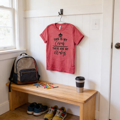 a red t-shirt hanging on a wall, a wooden bench with a backpack and a cup of coffee, and a pair of shoes on the floor.