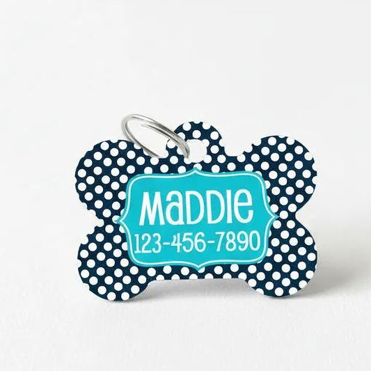 A blue and white polka dot dog tag with the name "Maddie" and a phone number.