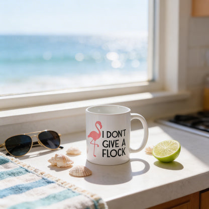 A mug with the text "I DON'T GIVE A FLOCK" sits on a kitchen counter, accompanied by a pair of sunglasses, a lime wedge, and some seashells.
