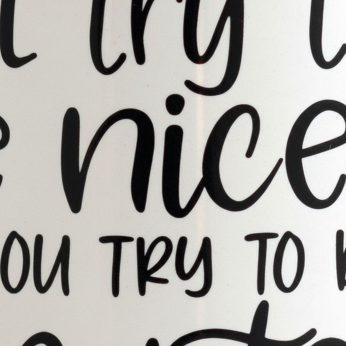 a close-up view of a white surface with black text that reads "TRY TO BE A NICE PERSON".