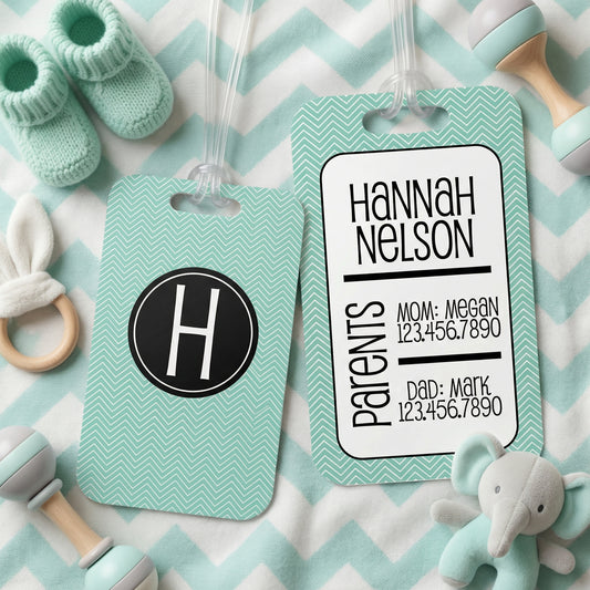 a baby tag with a monogrammed name, a baby bootie, and a stuffed elephant toy, all arranged on a chevron-patterned background.