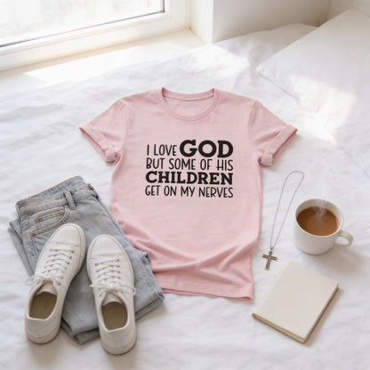A pink t-shirt with text, a pair of jeans, white sneakers, a cross necklace, a mug of coffee, and a notebook are arranged on a bed.