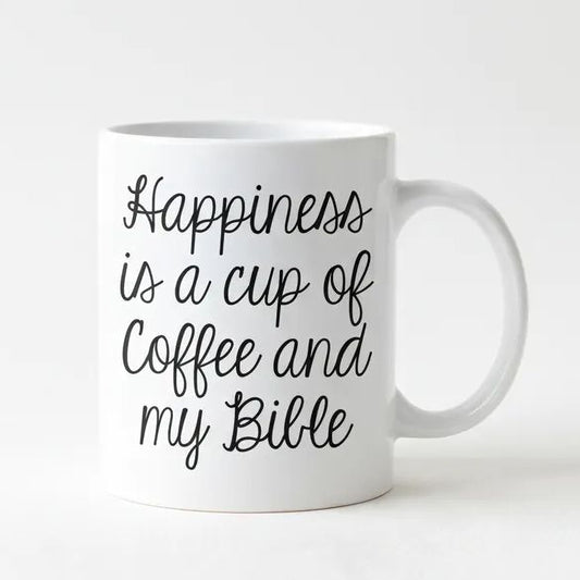 A white ceramic mug with black text that reads "Happiness is a cup of coffee and my Bible".
