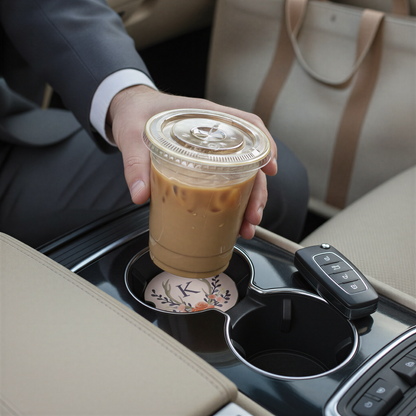 A person's hand is holding a cup of iced coffee in the car's cup holder.