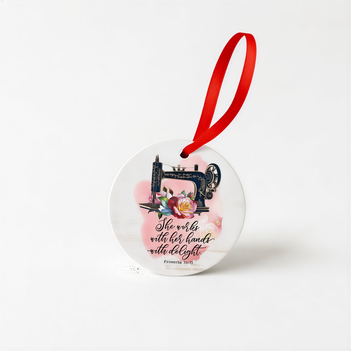 A round ceramic ornament with a sewing machine and floral design, along with a red ribbon.