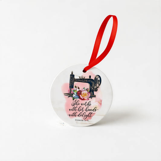 A round ceramic ornament with a sewing machine and floral design, along with a red ribbon.