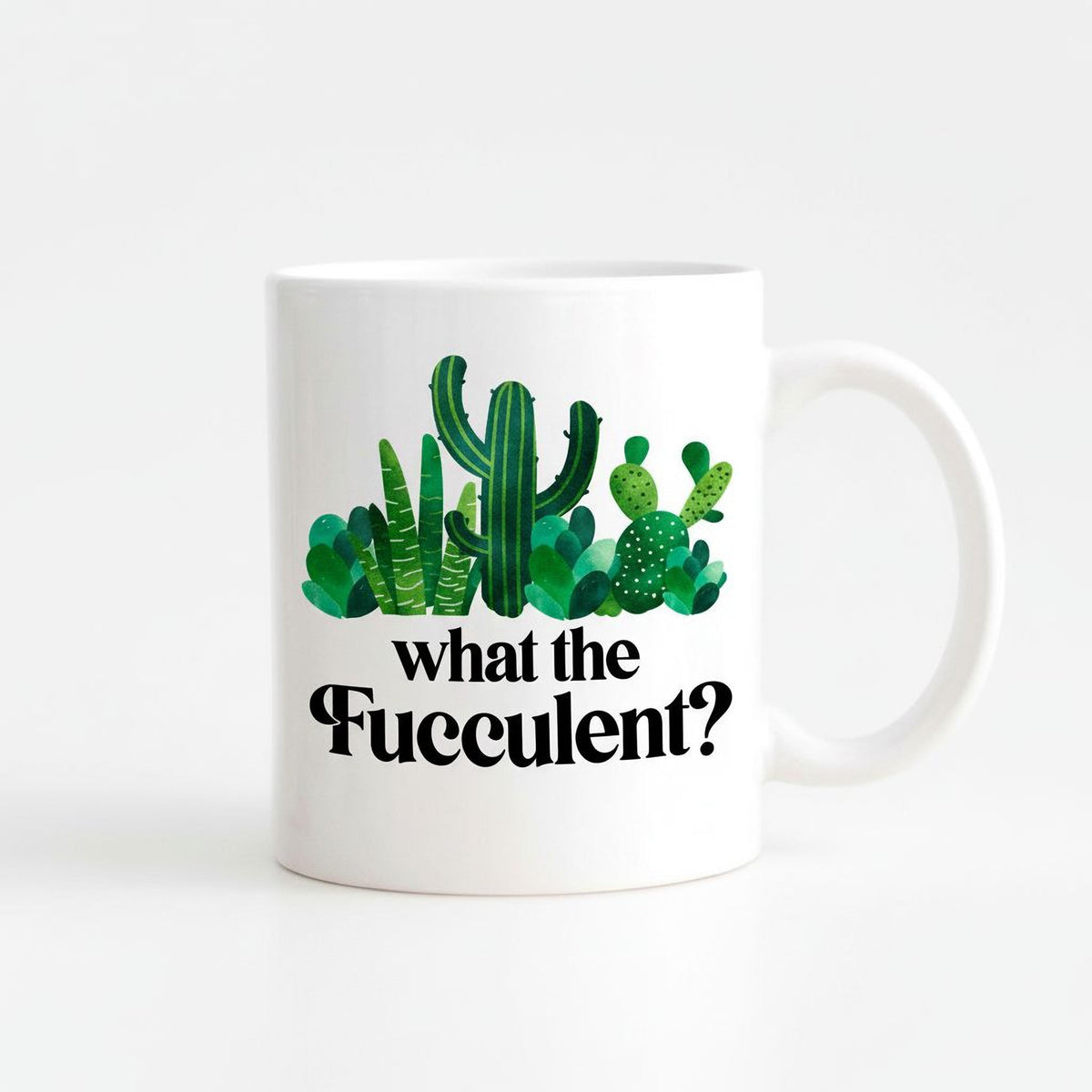 A white ceramic mug with a printed design of various cacti and succulents, along with the text "what the Fuzzy?"