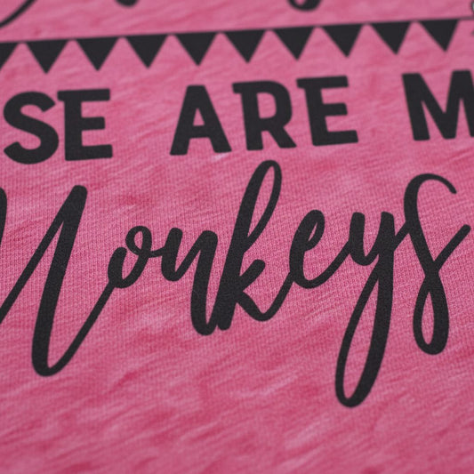 a close-up of a pink fabric with the text "Monkeys" printed on it in a cursive font.