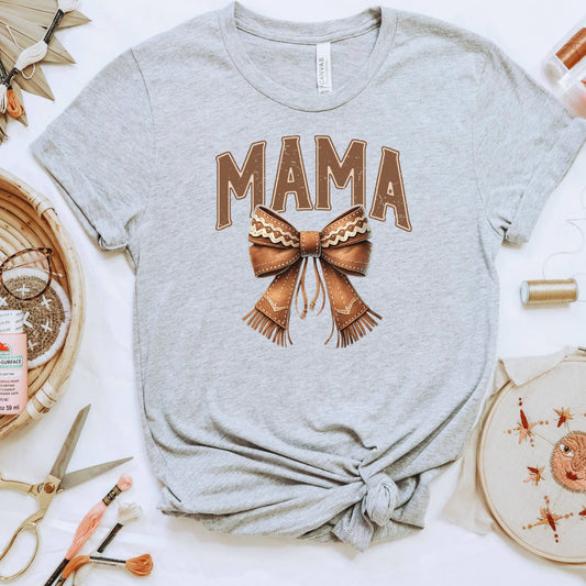 a grey t-shirt with a bow design, along with various crafting supplies such as scissors, embroidery floss, and a needle and thread.
