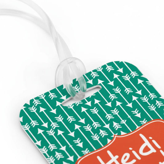 A green and white patterned luggage tag with a white ribbon attached to it.