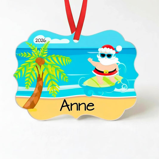 A personalized ornament featuring a cartoon Santa Claus riding a surfboard on a beach, with a palm tree and a cloud in the background.