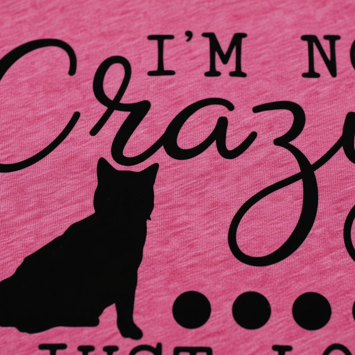 a close-up of a pink fabric with a black silhouette of a cat and the text "I'm not crazy just love" printed on it.