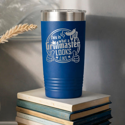 A blue tumbler with a printed design on it, sitting on top of a stack of books.
