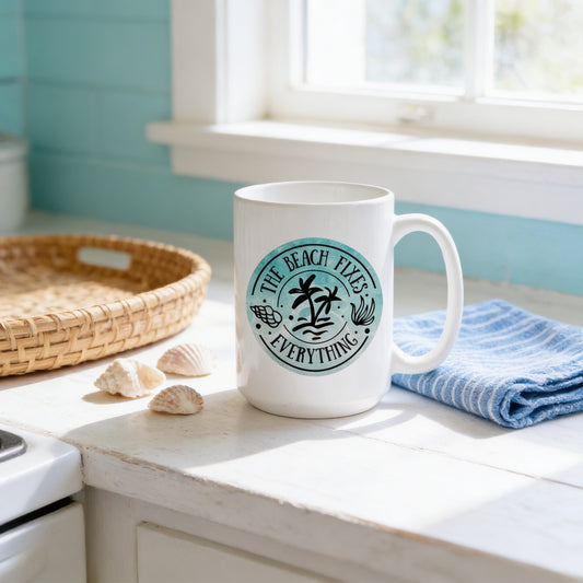 A white mug with a circular design featuring the text "The Beach Fix's Everything" sits on a kitchen counter next to a woven basket and some seashells.