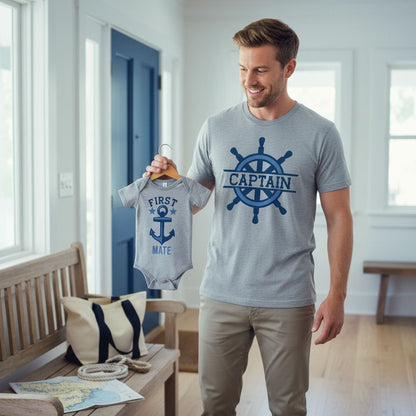 A man is holding a baby onesie with the text "FIRST MATE" and an anchor symbol, smiling as he displays the outfit.