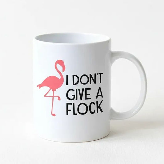 A white ceramic mug with a pink flamingo and the text "I DON'T GIVE A FLOCK" printed on it.