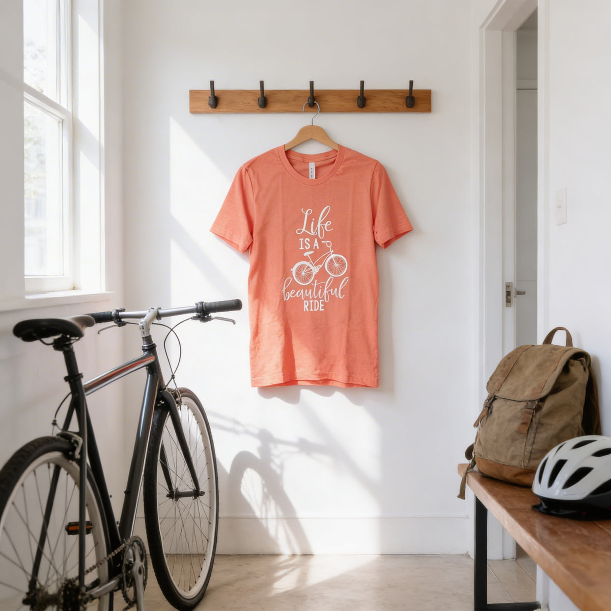 a bicycle, a t-shirt with a bicycle design, and a backpack, all displayed in a hallway.