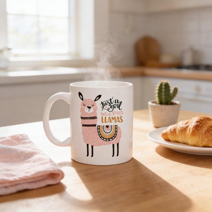 A mug with a cartoon image of a llama and the text "Just a girl who loves llamas" sits on a kitchen counter, with a plate of croissants and a potted cactus in the background.