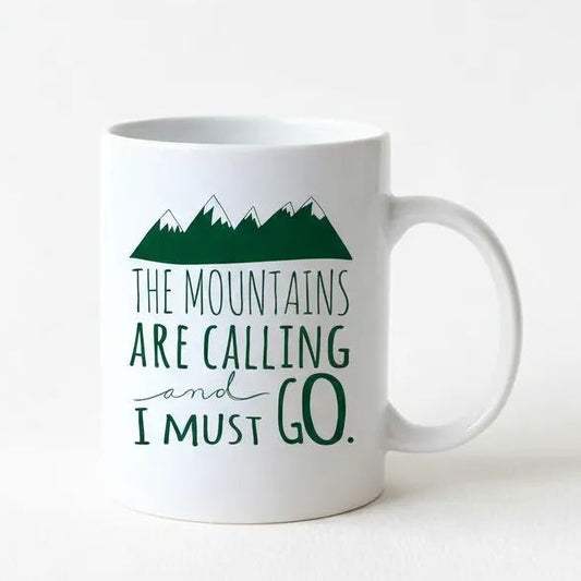 A white ceramic mug with a green mountain graphic and the text "The mountains are calling and I must go" printed on it.
