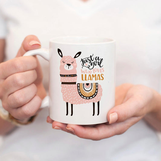A person is holding a white mug with a pink llama design on it.