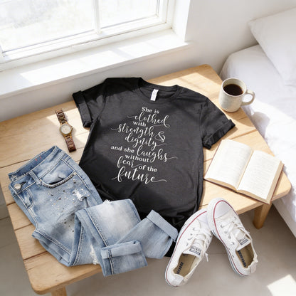 A casual outfit consisting of a black t-shirt with white text, blue jeans, and white sneakers is laid out on a wooden table, accompanied by a book and a cup of coffee.