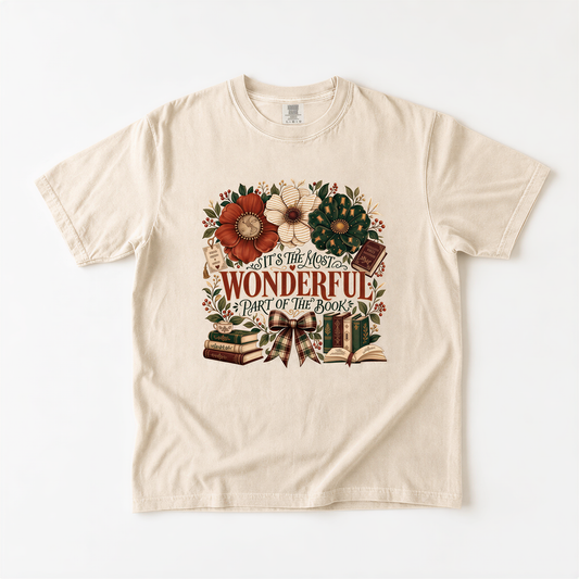 A beige t-shirt with a graphic design featuring a floral border and text that reads "It's the most wonderful part of the books".