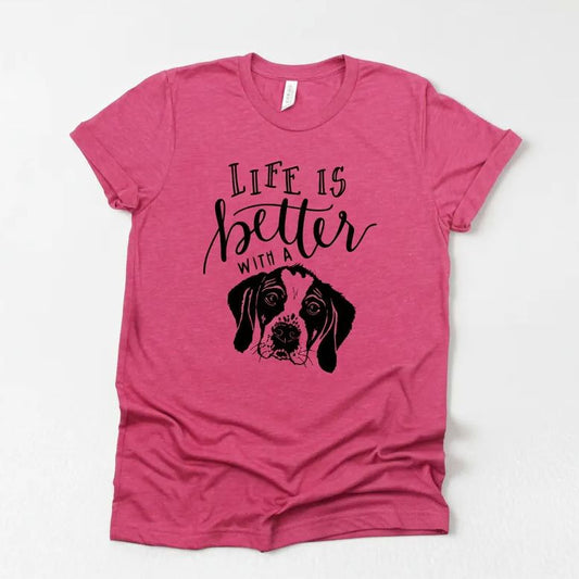 A pink t-shirt with a graphic design of a dog's face and the text "Life is better with a dog" printed on it.