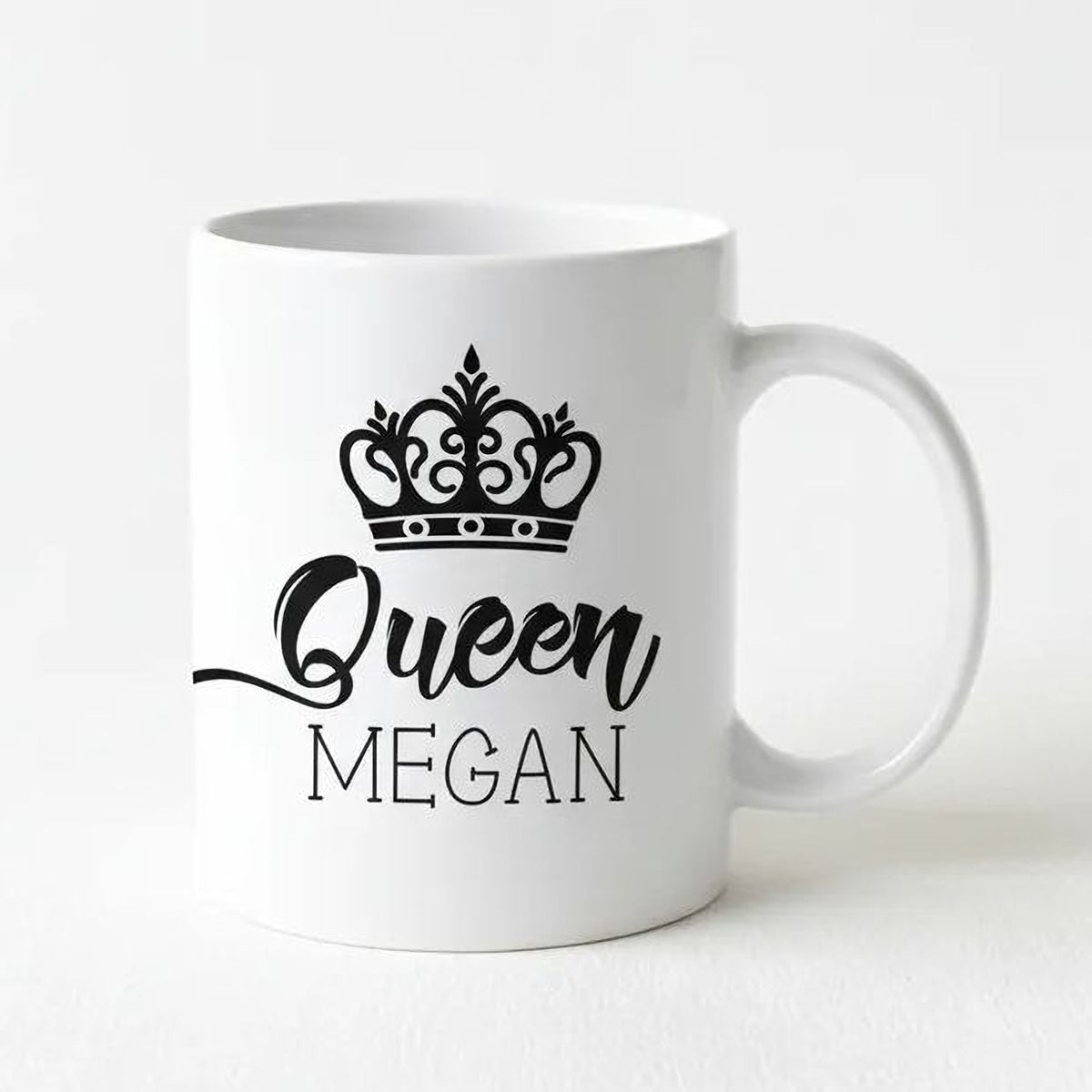 A white ceramic mug with a black crown design and the text "Queen Megan" printed on it.