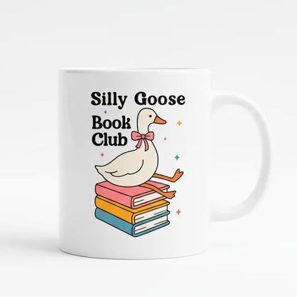 A white mug with a cartoon image of a white goose sitting on a stack of colorful books, with the text "Silly Goose Book Club" written above it.
