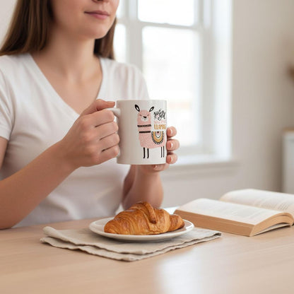A woman is sitting at a table, holding a mug with a cartoon character on it, and enjoying a croissant and a book.