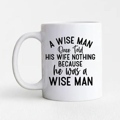 A white ceramic mug with black text that reads "A WISE MAN Once folded his WIFE NOTHING BECAUSE he was a WISE MAN".