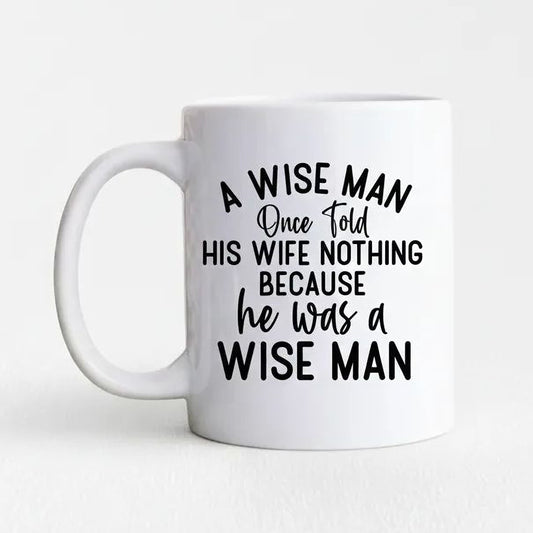 A white ceramic mug with black text that reads "A WISE MAN Once folded his WIFE NOTHING BECAUSE he was a WISE MAN".