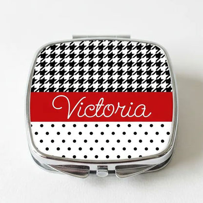 A compact mirror with a black and white houndstooth pattern and the name "Victoria" written in cursive on the front.