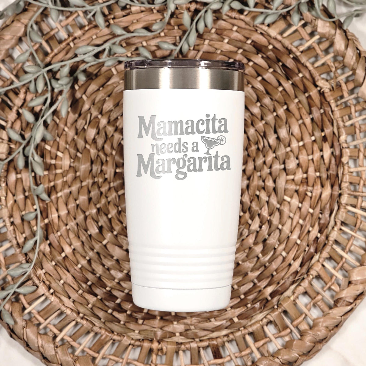 A white insulated tumbler with a printed text on it, placed on a woven placemat.