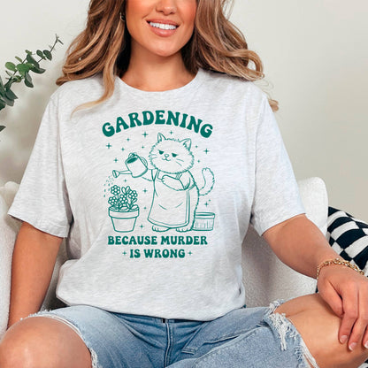 A woman wearing a grey t-shirt with a graphic design of a cat watering plants and the text "GARDENING BECAUSE MURDER IS WRONG" printed on it.