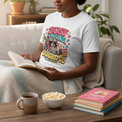 A person is sitting on a couch, reading a book and enjoying snacks, including popcorn and a cup of coffee.