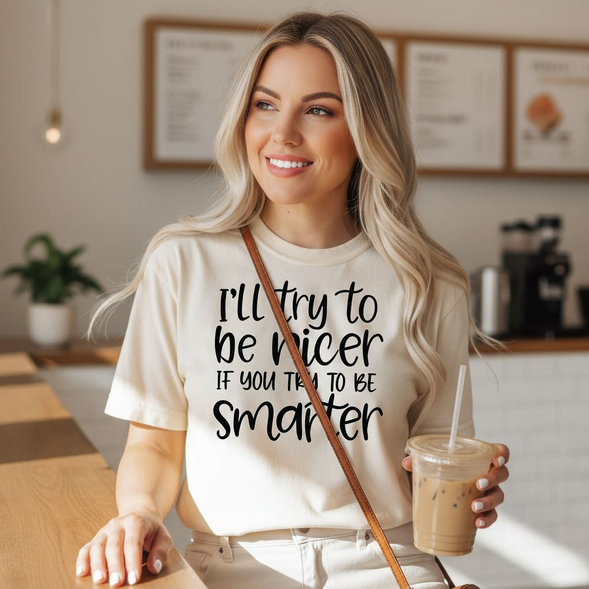 A smiling woman wearing a white t-shirt with text printed on it, holding a drink in a plastic cup.