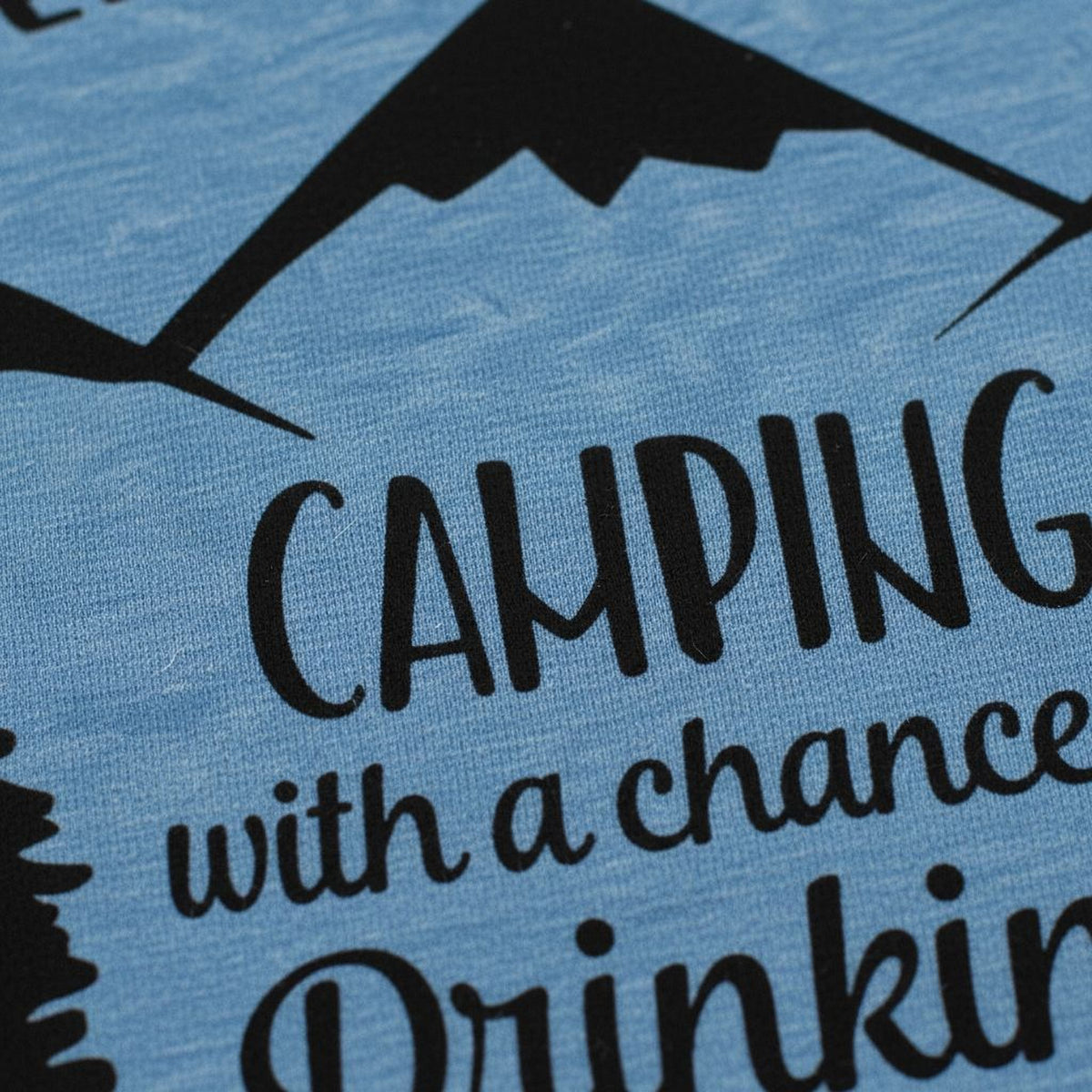 a close-up view of a blue fabric with a black silhouette of a mountain and the text "CAMPING" prominently displayed.