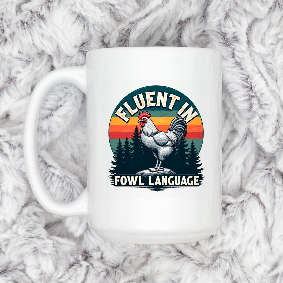 A white mug with a graphic design featuring a rooster and the text "FLUENT IN FOWL LANGUAGE" against a sunset background.