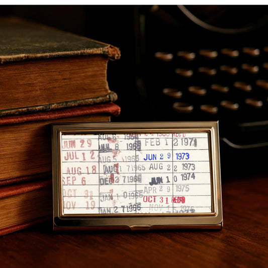 a small, rectangular card with a list of dates and events, placed on a wooden surface next to a stack of books.