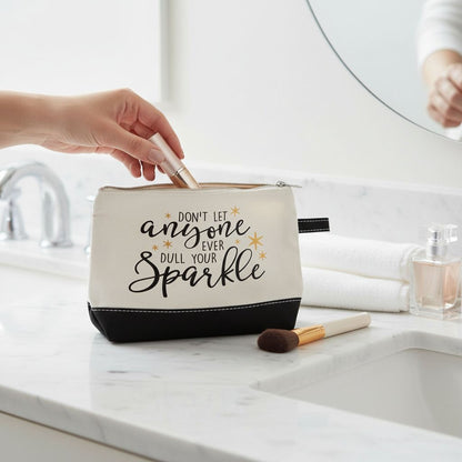 A hand is holding a makeup brush out of a makeup bag with a motivational quote printed on it.