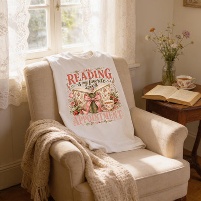 A cozy reading nook in a room with a beige armchair, a white t-shirt with a floral design, and a vase of flowers on a small table.